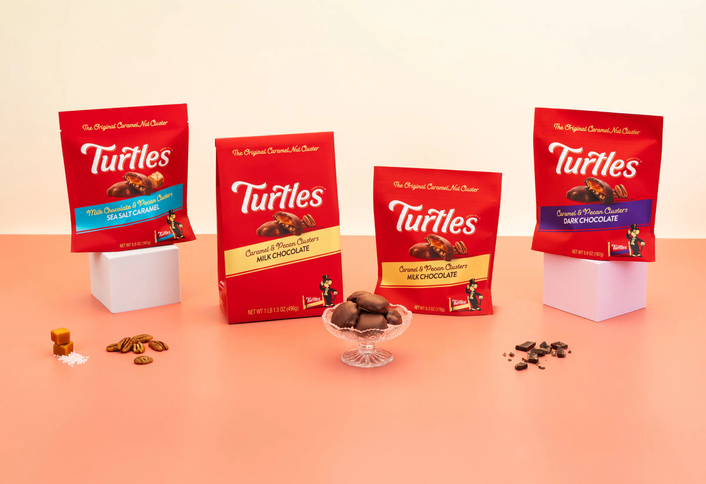 Turtles bags in four flavours on a peach set, with pecans, caramels and a dish of Turtles